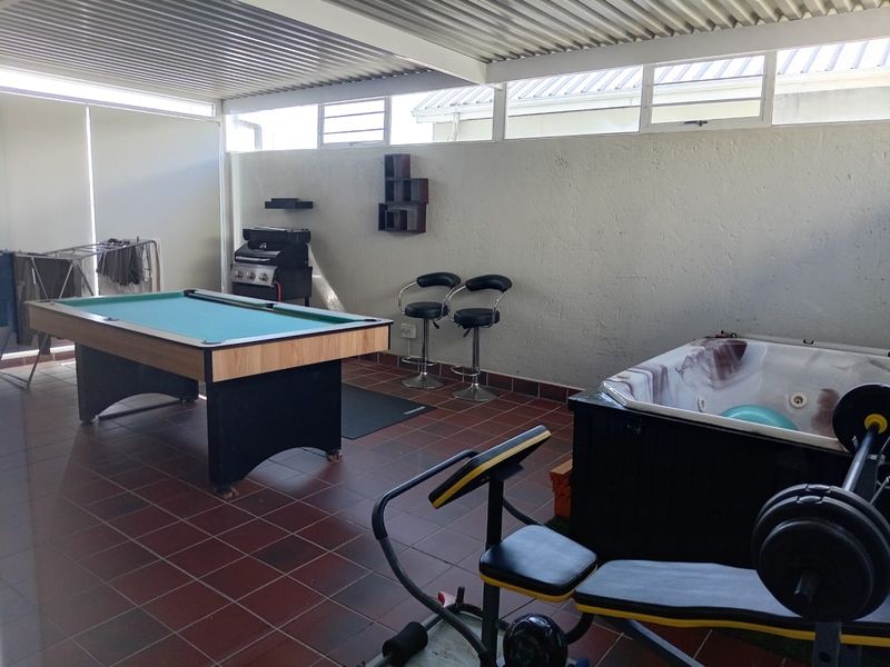 Covered patio area featuring tiled flooring, a built-in jacuzzi, and louvre windows, suitable for an entertainment or leisure space.
