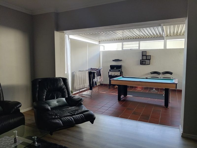 A covered patio area featuring tiled flooring and corrugated roofing, providing a versatile space for outdoor entertainment and relaxation.