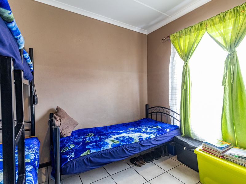 A functional bedroom featuring tiled flooring and neutral wall finishes, offering a practical space with natural light from the window.