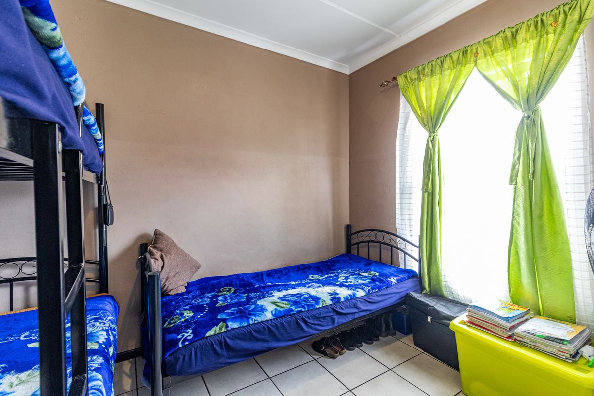 A functional bedroom featuring tiled flooring and neutral wall finishes, offering a practical space with natural light from the window.