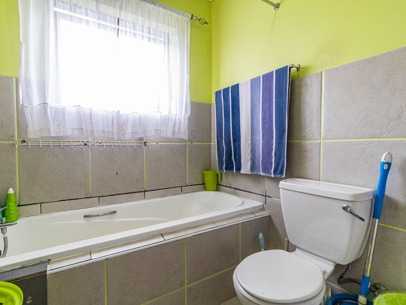 A functional bathroom featuring a bathtub, toilet, and neutral wall tiling with bright accent walls, offering a practical layout for daily use.