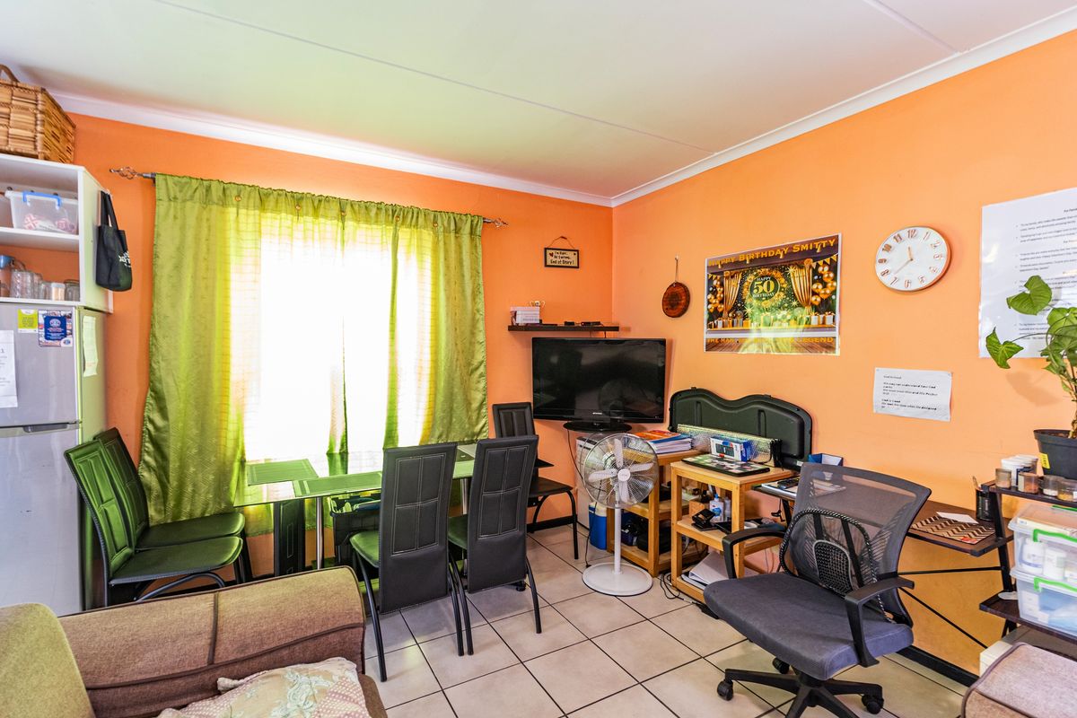 A living area featuring tiled flooring and a window with curtain rod, currently utilized as a multi-purpose space.