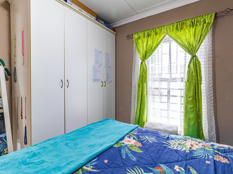 A bedroom featuring a built-in wardrobe and a window fitted with security bars.