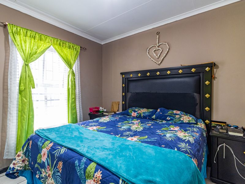A standard bedroom featuring neutral wall tones, a window with security bars, and coving detail.