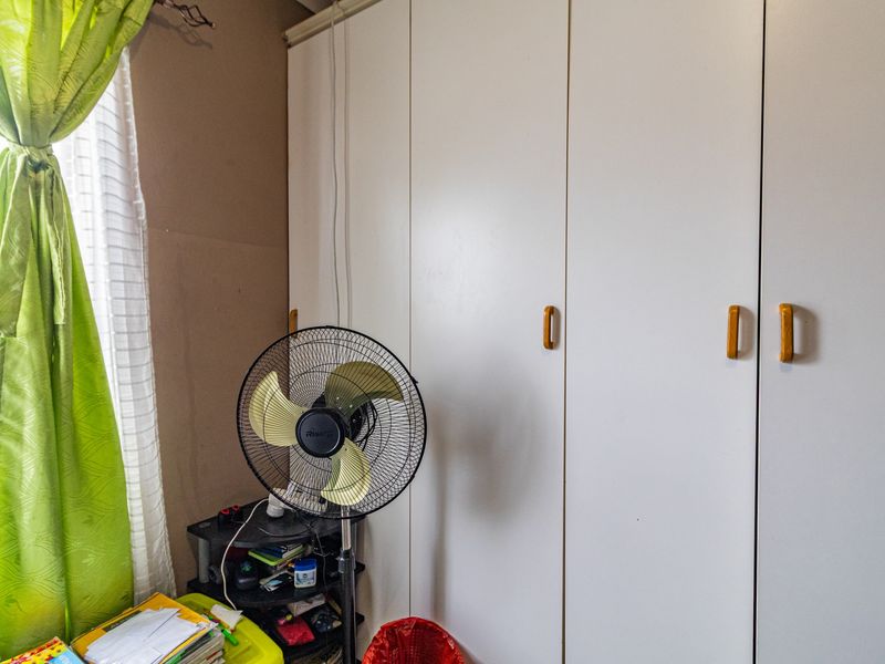 A bedroom featuring a large white built-in wardrobe with wooden handles, providing ample storage space.