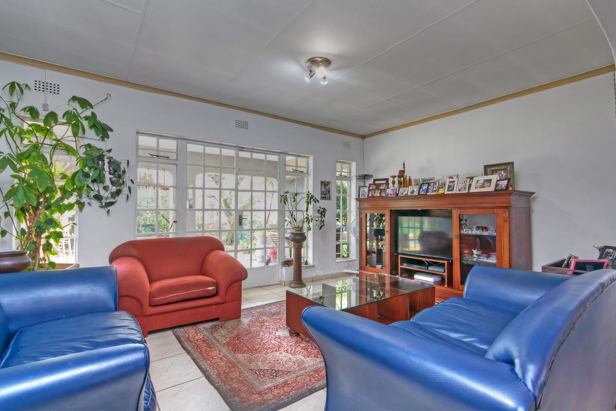 A living room featuring tiled flooring and large french doors providing natural light and access to the outdoor area.