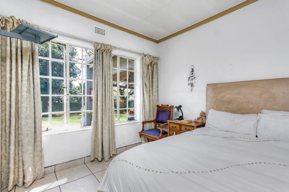 A bedroom featuring tiled flooring and large multi-pane windows that provide natural light and views of the garden.