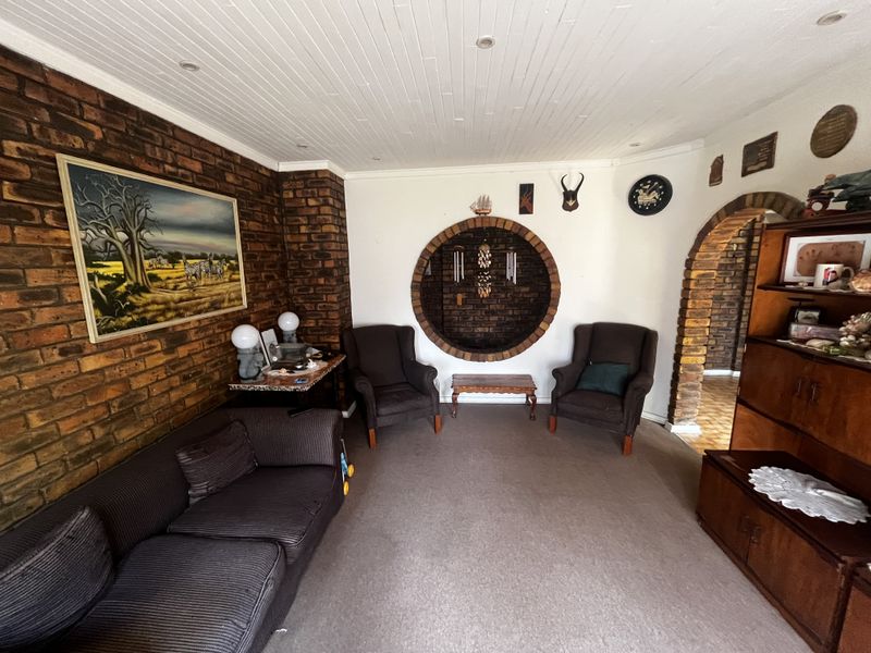 Living room featuring exposed brick walls, a unique circular brick feature, and a classic brick archway leading to an adjacent space.