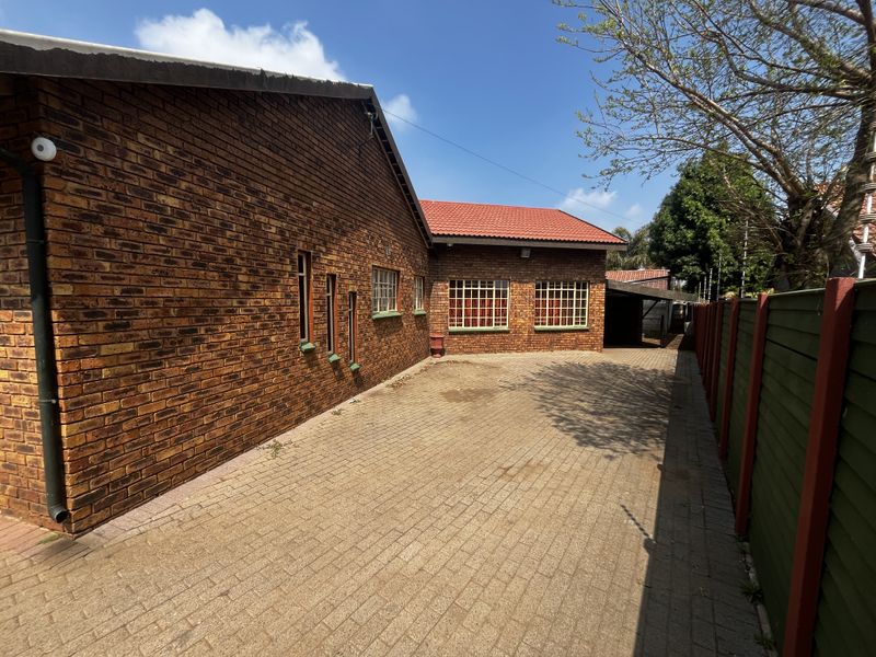 A well-maintained face-brick exterior featuring a spacious paved driveway, secure window bars, and a durable tiled roof.