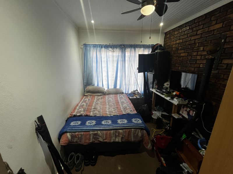 A bedroom featuring an exposed brick feature wall, tongue and groove ceiling with a fan, and recessed lighting.