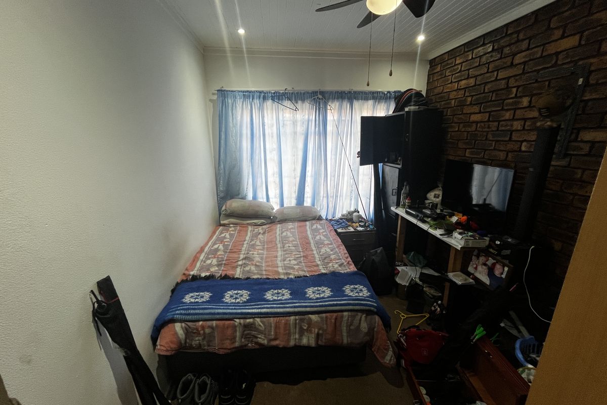 A bedroom featuring an exposed brick feature wall, tongue and groove ceiling with a fan, and recessed lighting.
