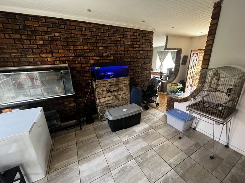 Living area featuring a prominent exposed brick feature wall, tiled flooring, and an arched transition leading to an adjacent space.