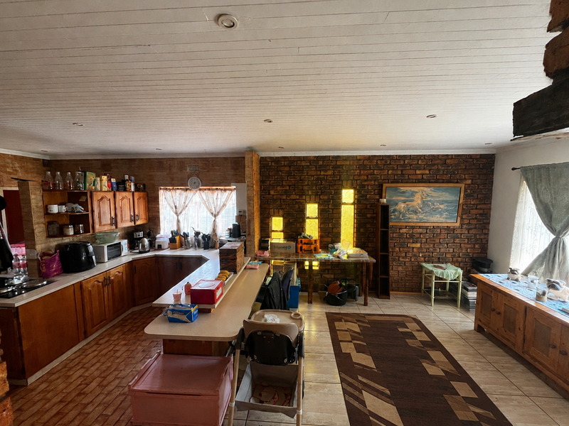 Spacious open-plan kitchen and living area featuring rustic exposed brick walls, timber ceiling, and traditional wooden cabinetry with ample counter space.