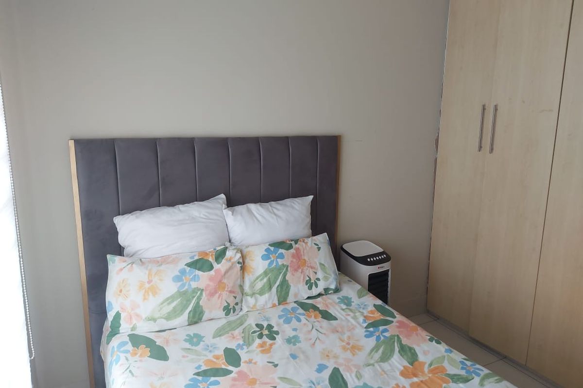 A bedroom featuring a built-in wardrobe with light wood finish and neutral wall tones.
