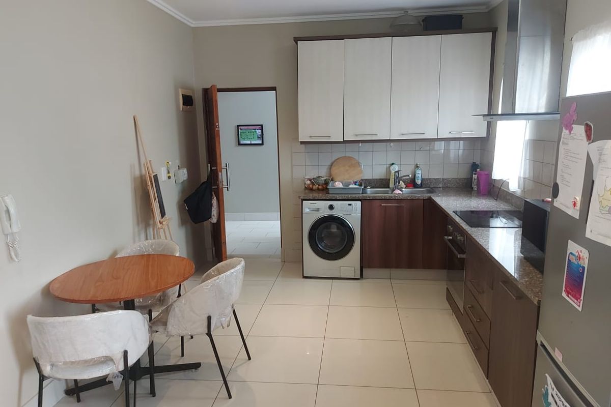Functional kitchen featuring built-in cabinetry, granite countertops, integrated washing machine, and stainless steel appliances with tiled flooring throughout.