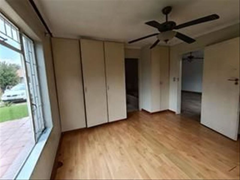 A spacious bedroom featuring built-in cupboards, a ceiling fan, and laminate flooring, offering a blank canvas for personalization.