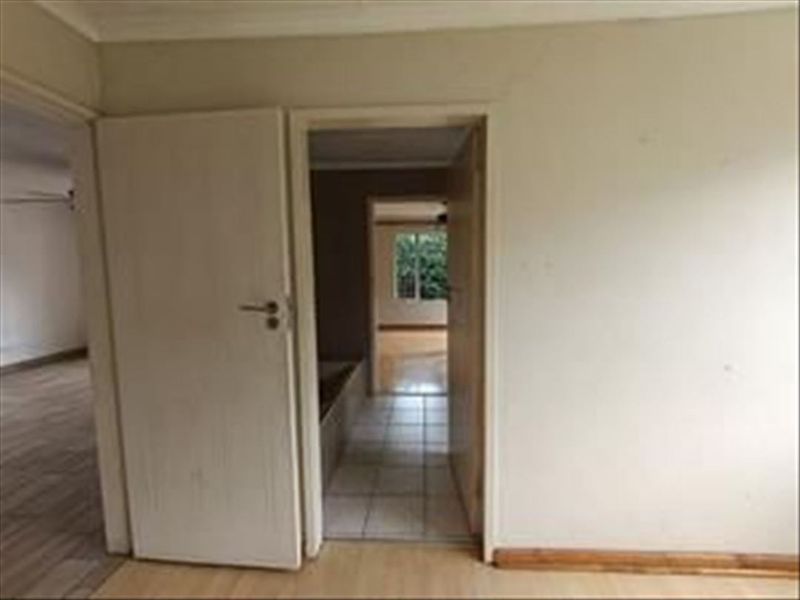 A view through a hallway showing tiled flooring and connecting doorways, featuring visible plaster cracking above the door frame.