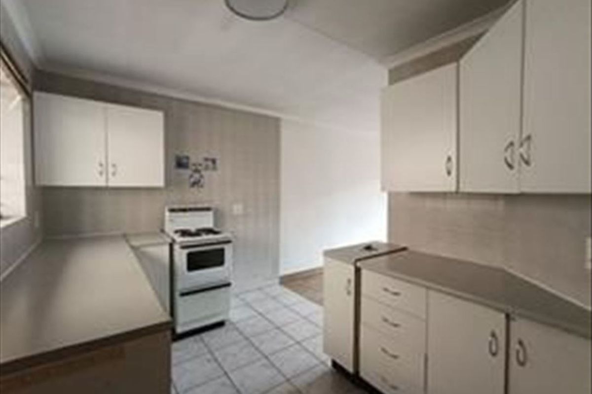 A functional kitchen featuring white built-in cabinetry, laminate countertops, and tiled flooring, providing a clean and practical workspace.