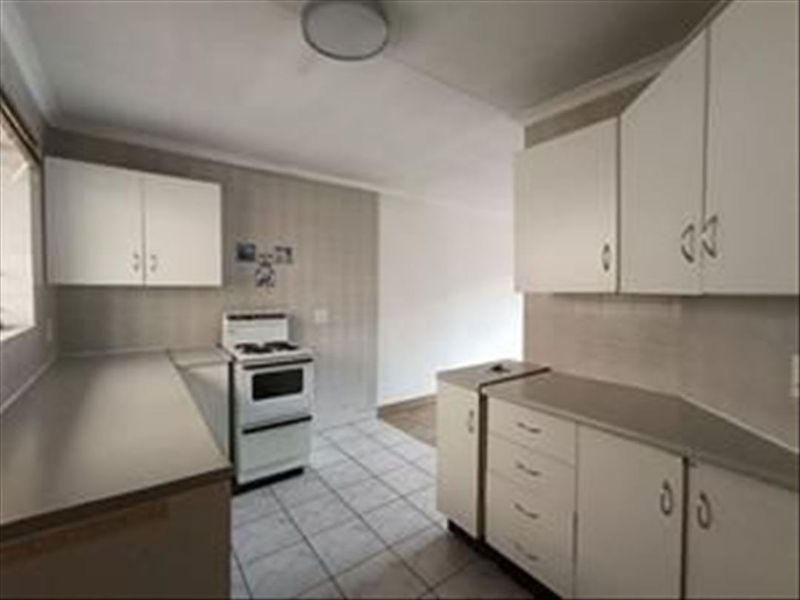 A functional kitchen featuring white built-in cabinetry, laminate countertops, and tiled flooring, providing a clean and practical workspace.