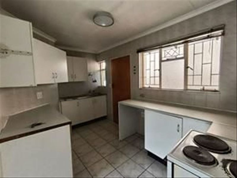 A functional kitchen featuring built-in cabinetry, tiled flooring, and an electric stove, offering a blank canvas for potential modern updates.
