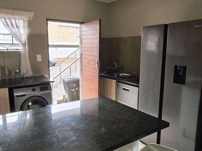 A functional kitchen featuring a granite-topped island, tiled flooring, and direct access to an outdoor area.