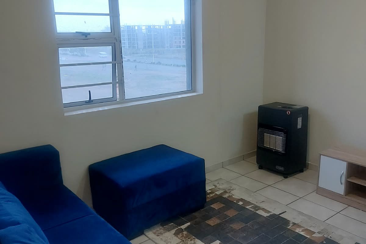 A living room featuring tiled flooring, a window with security bars, and a roller blind, providing a functional and neutral space.