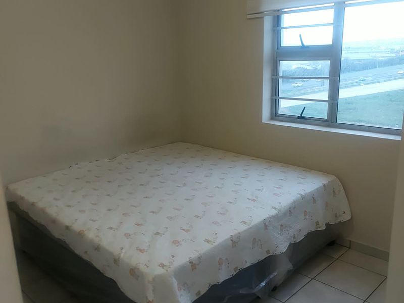 A simple bedroom featuring tiled flooring, a window with security bars, and a roller blind.
