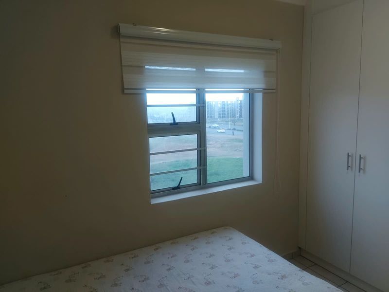 A bedroom featuring a built-in wardrobe, a window with security bars, and a roller blind.
