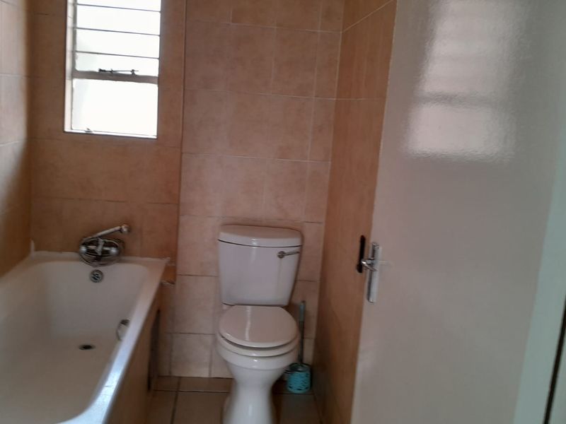 A functional bathroom featuring a standard bathtub, toilet, and tiled finishes, offering a blank canvas for potential modernization and renovation.