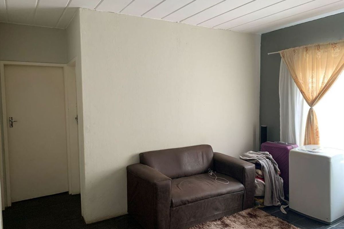 A living area featuring tiled flooring and a panelled ceiling, providing a functional space for relaxation.
