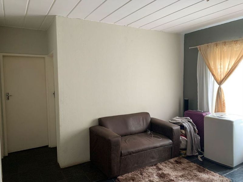 A living area featuring tiled flooring and a panelled ceiling, providing a functional space for relaxation.