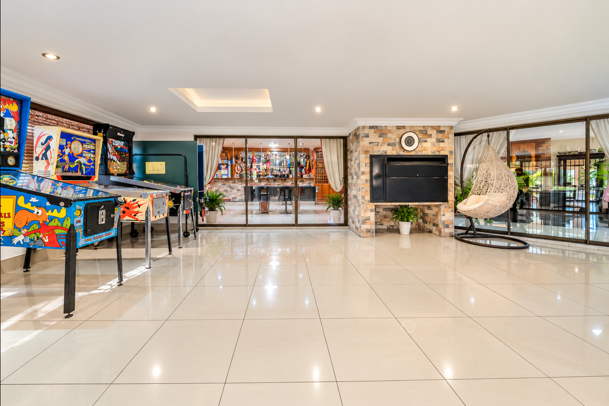 Spacious living area featuring large porcelain floor tiles, a stone-clad fireplace, and sliding glass doors leading to an adjacent bar area.