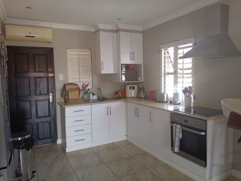 A functional kitchen featuring white cabinetry, stainless steel appliances, tiled flooring, and plantation shutters, providing a clean and practical cooking space.