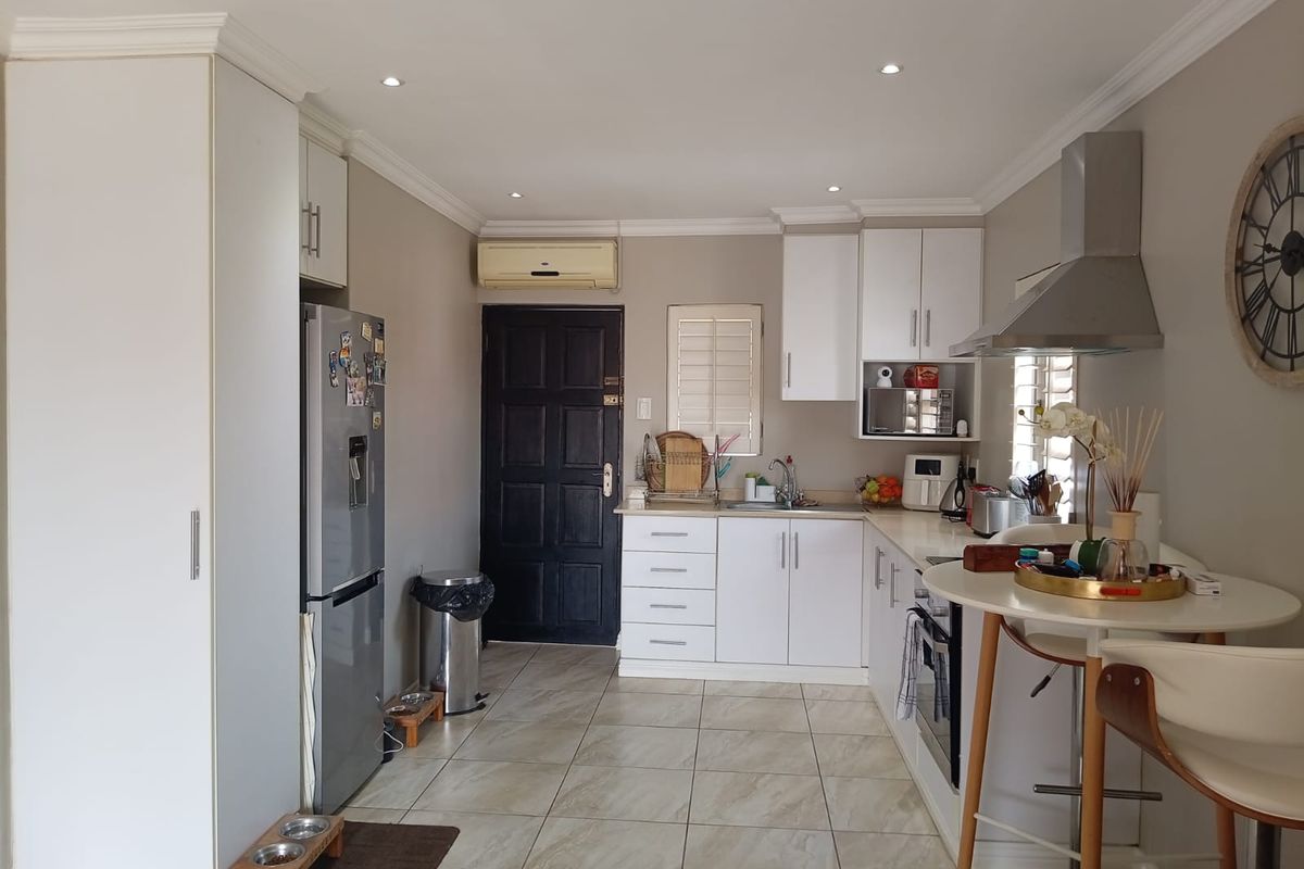 A functional kitchen featuring white cabinetry, tiled flooring, built-in oven, stainless steel extractor fan, and recessed lighting.