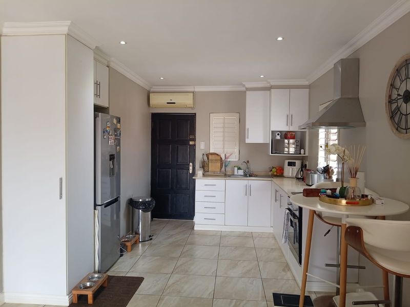 A functional kitchen featuring white cabinetry, tiled flooring, built-in oven, stainless steel extractor fan, and recessed lighting.