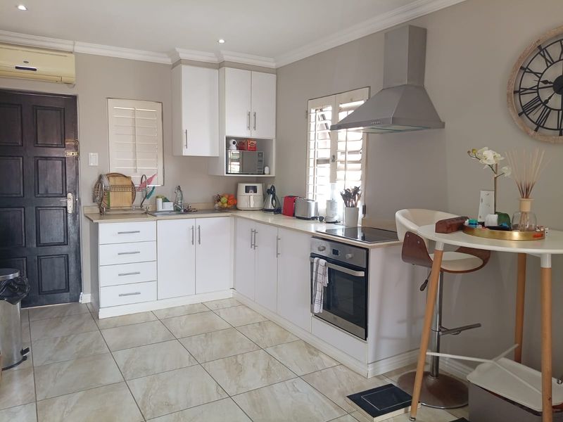 A functional kitchen featuring white cabinetry, stainless steel appliances, tiled flooring, and plantation shutters, providing a clean and well-maintained cooking space.