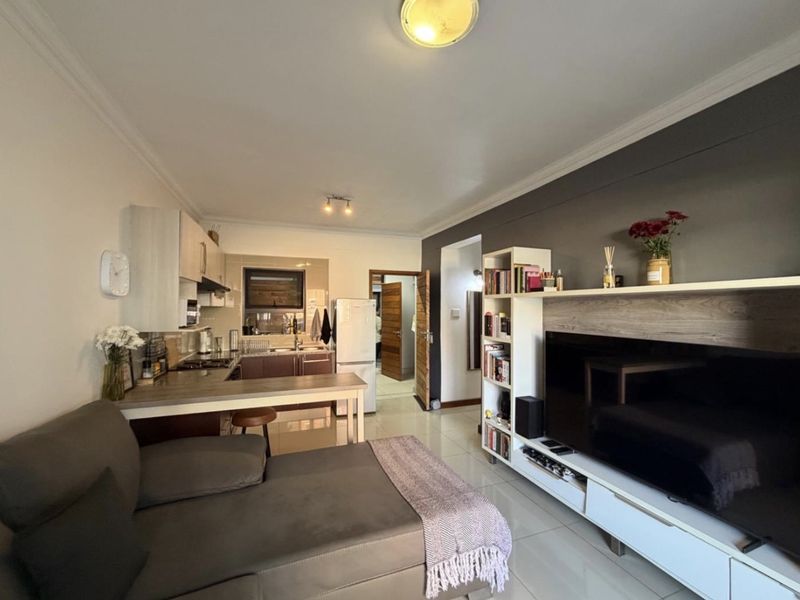 Open-plan living area featuring a compact kitchen with built-in cabinetry, tiled flooring, and a modern layout connecting to the main living space.