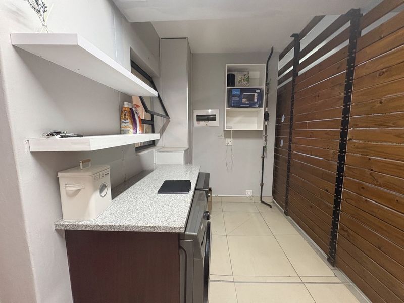 A functional laundry area featuring tiled flooring, granite countertops, built-in shelving, and a decorative timber slat wall panel.