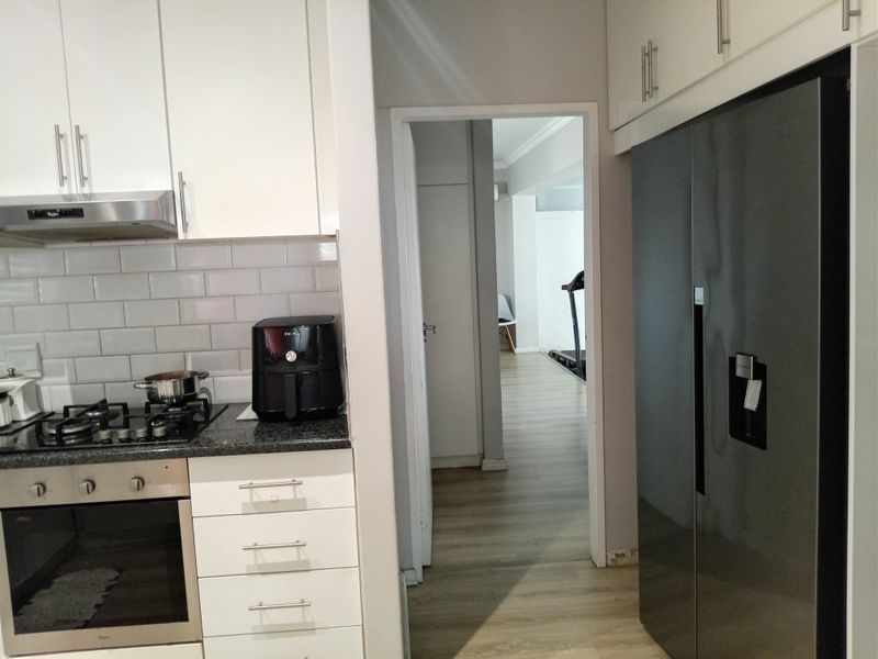 Modern kitchen featuring white cabinetry, subway tile backsplash, gas hob, and built-in oven, with a view through to the adjacent living area.
