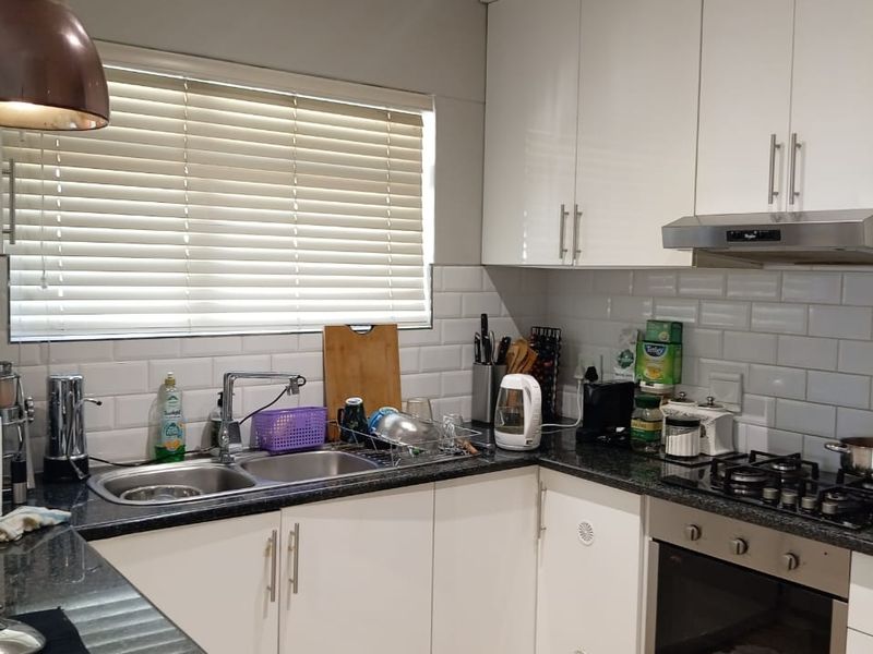 Modern kitchen featuring white gloss cabinetry, granite countertops, subway tile backsplash, and integrated stainless steel appliances including an oven and gas hob.