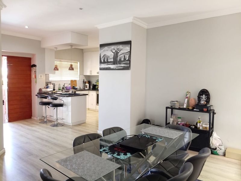 Open-plan living and dining area featuring a modern kitchen with a central island, laminate flooring, and neutral finishes throughout.