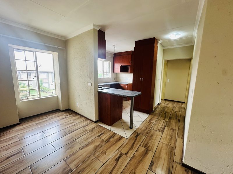 Open-plan kitchen and living area featuring wood-look laminate flooring, tiled kitchen zone, built-in cabinetry, and a breakfast nook.