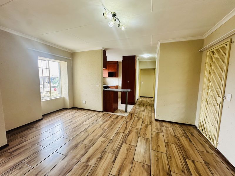 Open plan living and kitchen area featuring wood-look tile flooring, built-in cabinetry, and a breakfast counter in a neutral setting.