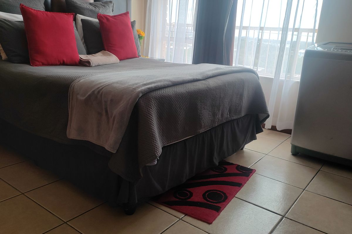 A bedroom featuring tiled flooring and a sliding glass door providing natural light and access to an outdoor area.