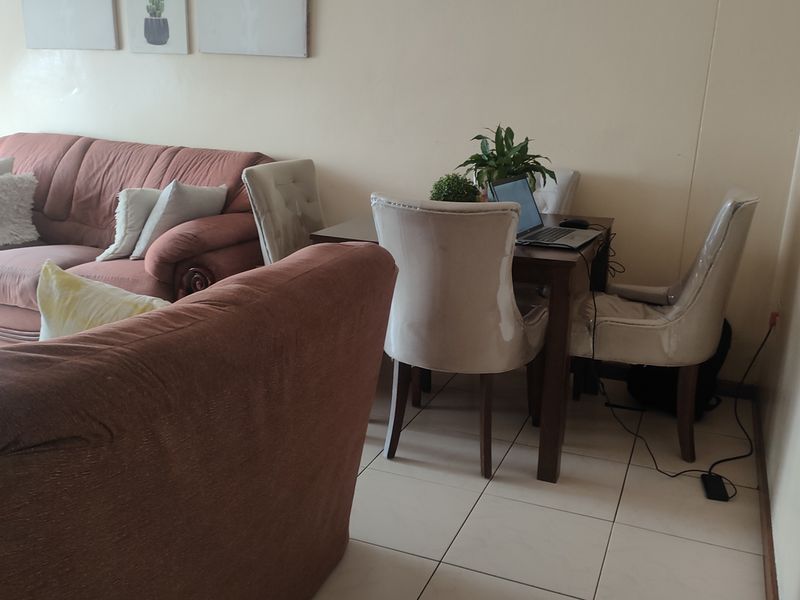 A living room area featuring tiled flooring and neutral wall finishes, providing a functional space for relaxation and dining.