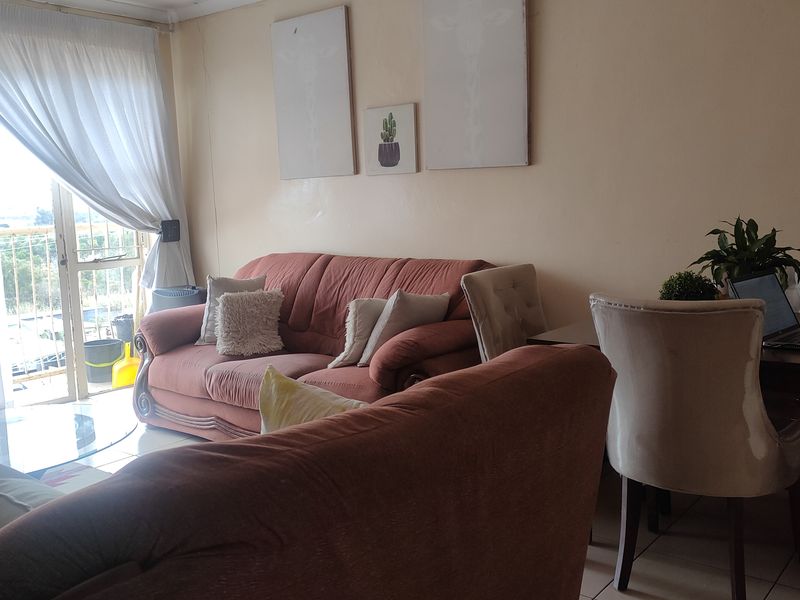 A living room area featuring tiled flooring and a sliding glass door providing access to an outdoor space.