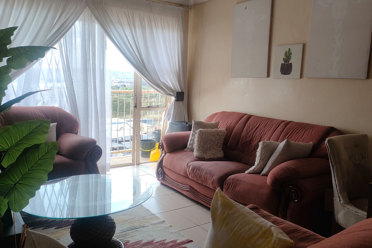 A living room area featuring tiled flooring and a sliding glass door that provides access to an outdoor balcony space.