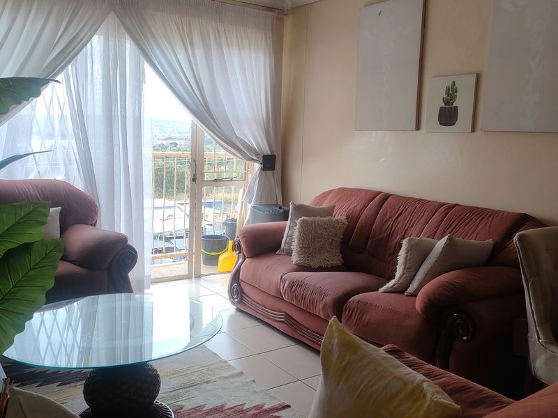 A living room area featuring tiled flooring and a sliding glass door that provides access to an outdoor balcony space.