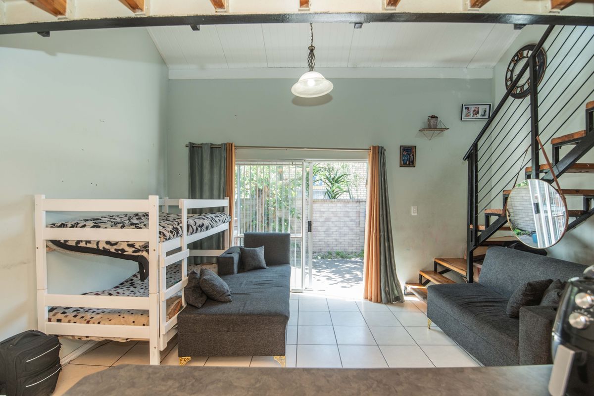 Open-plan living area featuring tiled floors, a metal staircase, and a sliding glass door providing access to the outdoor space.