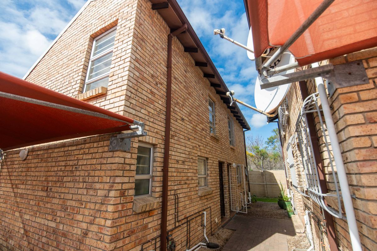 A side view of the face brick apartment building featuring paved walkways, retractable awnings, and installed satellite dishes.